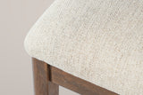 Close-up of the beige woven seat fabric, the wooden apron and a walnut-finished leg