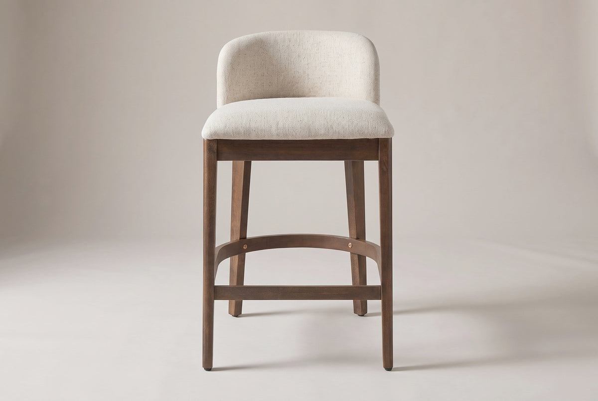 Torgiano counter stool, straight front view: low curved padded back, four tapered legs and a bent-wood footrest