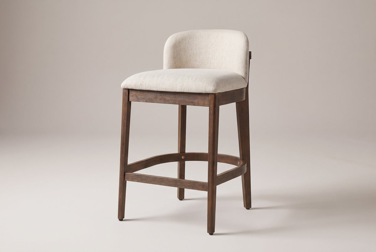 Torgiano counter stool in Walnut with a beige seat, three-quarter view on a warm light-grey studio backdrop