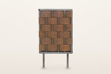 The end of the Trequanda sideboard in Brown on a warm white studio backdrop: the same leather weave as the doors