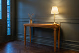 Treviso console table in a green-grey panelled Toronto front hall in the evening, a brass lamp lit at one end