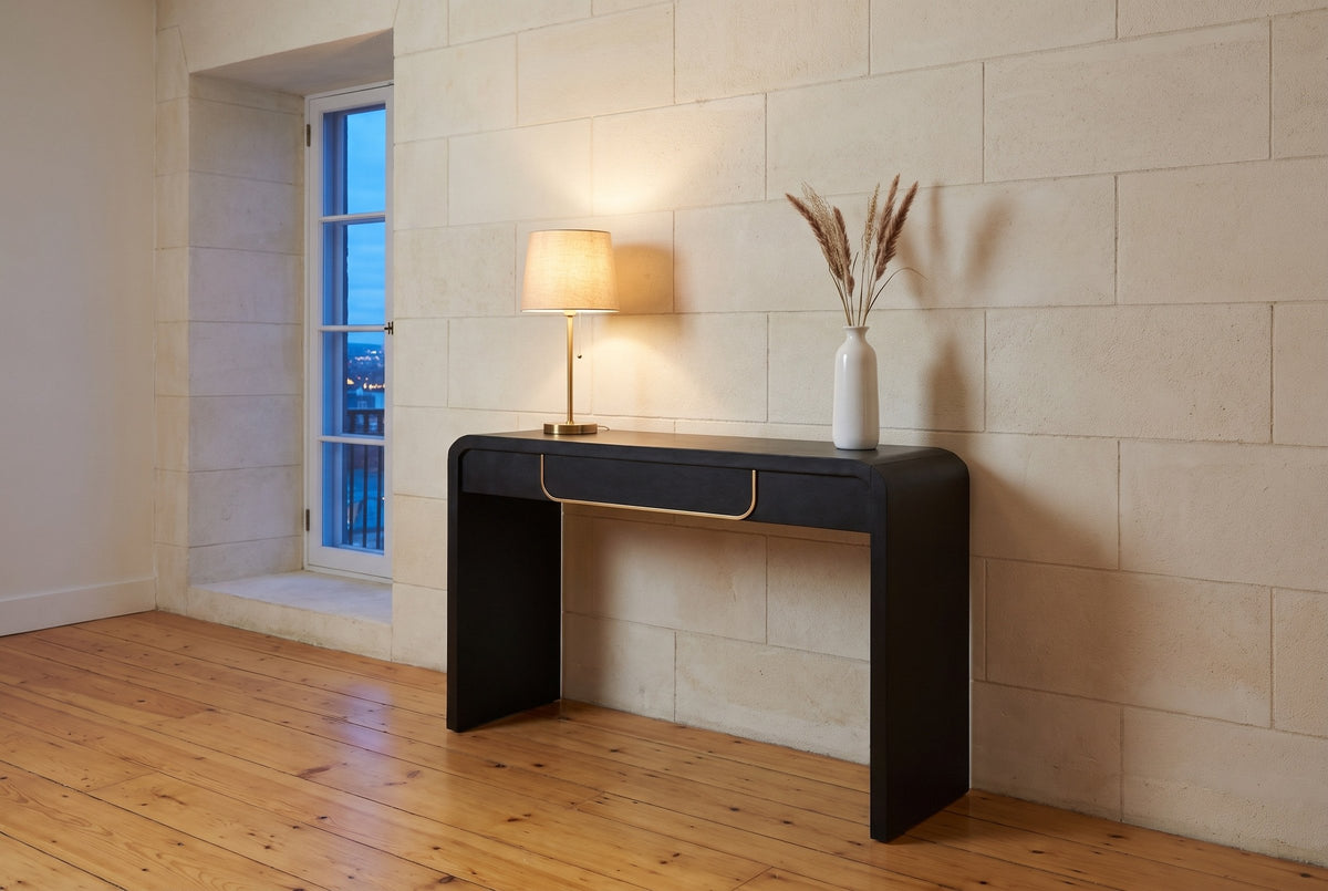 Trieste console table against a pale limestone wall in a Quebec City hall at dusk
