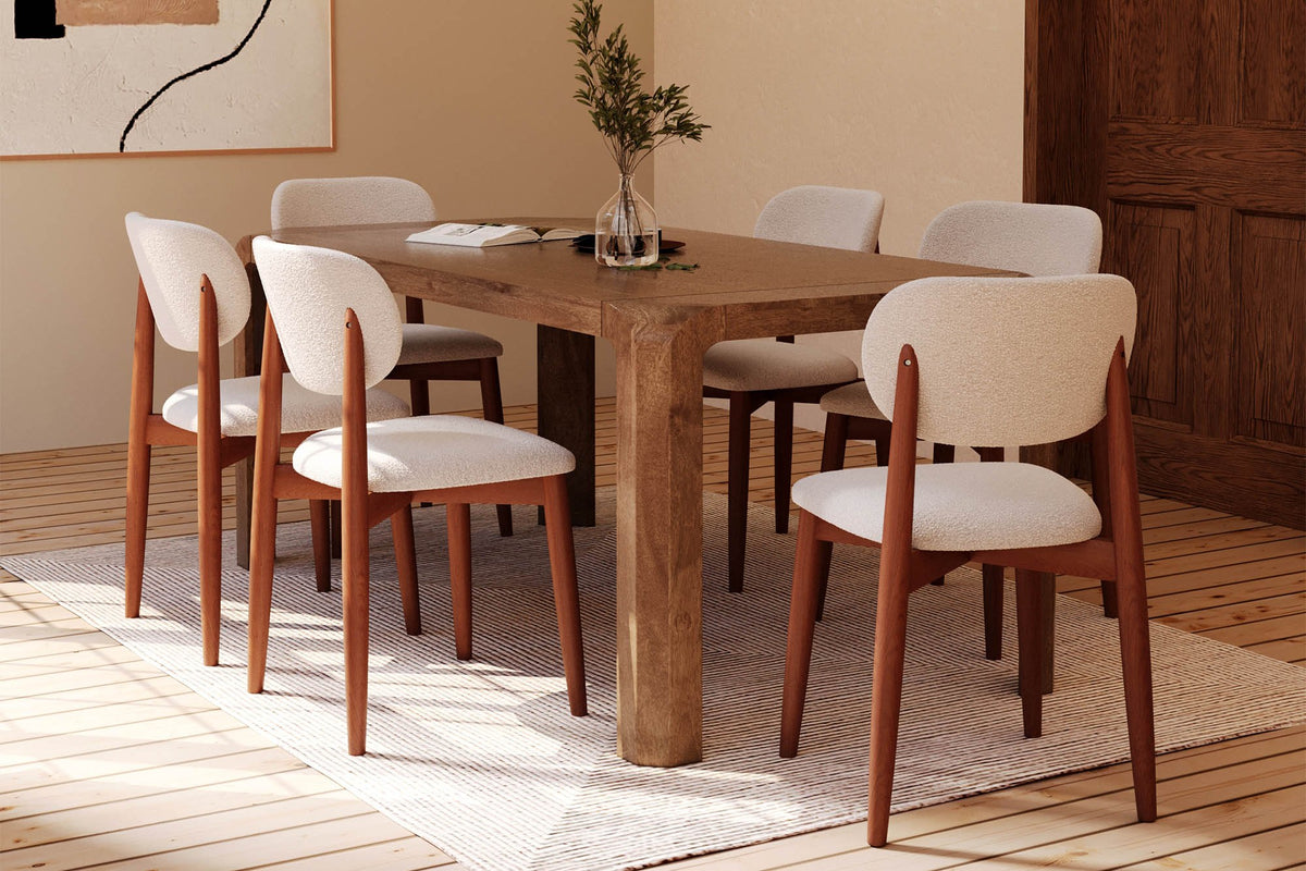 Tristan brown dining table with six upholstered chairs beside a wooden arched door