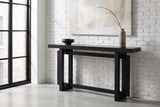 Urbania console table against a whitewashed brick wall in a loft entry, a branch in a stoneware vase