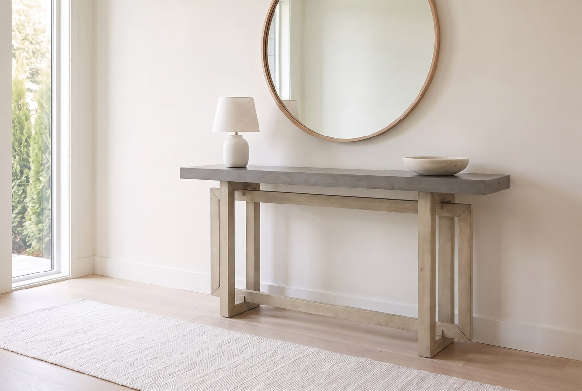 Urbania console table in Gray in a bright entry under a round oak mirror, a white lamp and a stone bowl on top