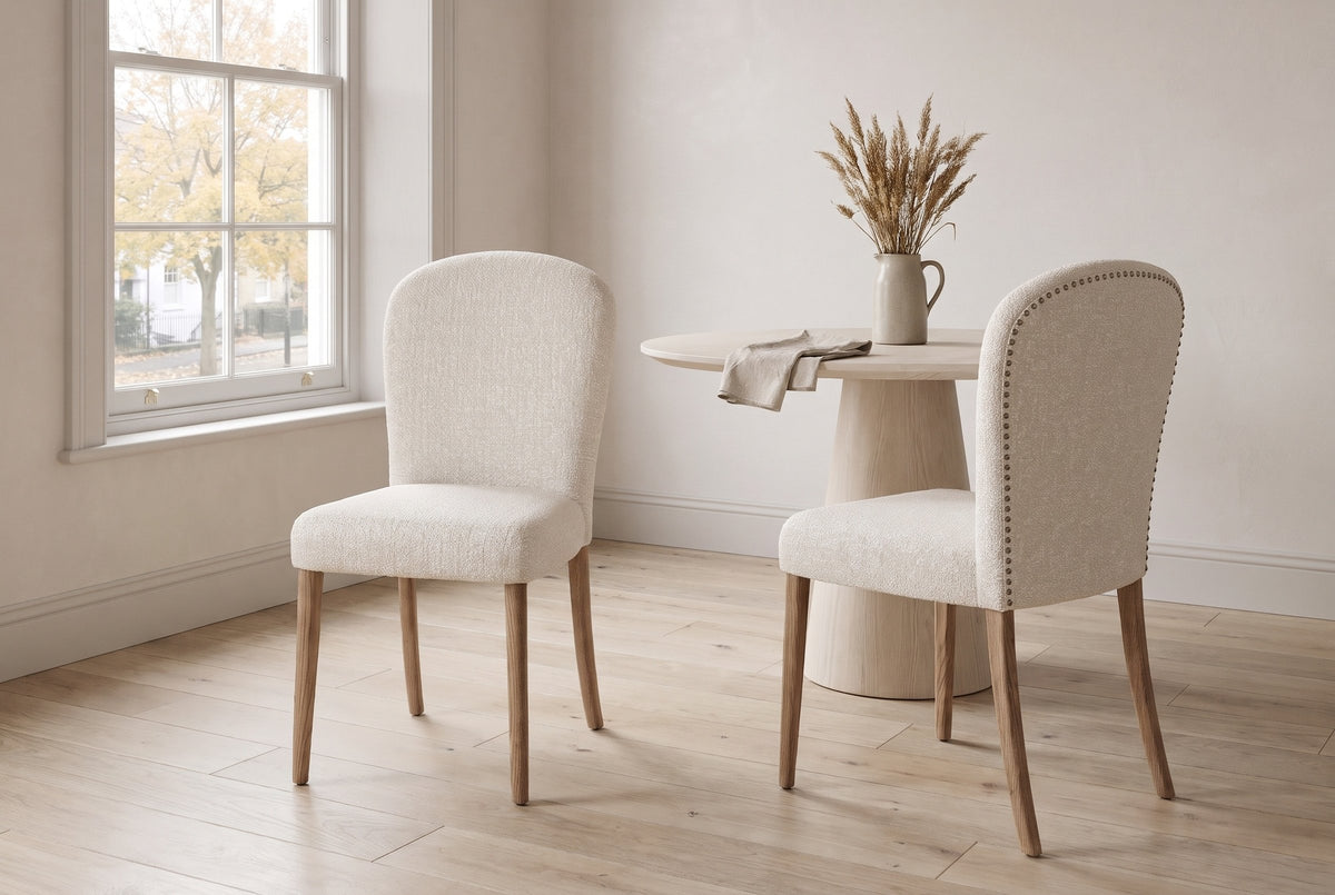 Two Usseglio dining chairs in cream woven fabric on brown ash legs beside a pale round oak table in an Ottawa Glebe dining room, an autumn maple through the window