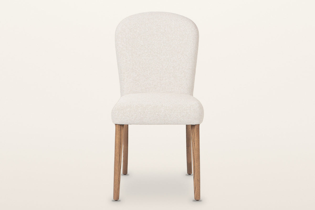 Usseglio dining chair, straight front view: the arched upholstered back, the thick seat and four ash legs