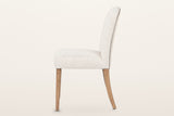 Usseglio dining chair from the side: the back curving gently backward, the nailhead line along its rear edge and the swept-back rear legs