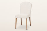 Usseglio dining chair in cream woven fabric on brown ash legs, three-quarter view on a warm white studio backdrop