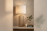 Valeria glass table lamp glowing on a stone console beside a small vase