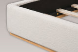 Close-up of the foot corner of the Varenna bed: the rounded boucle rail on its recessed natural rubberwood plinth