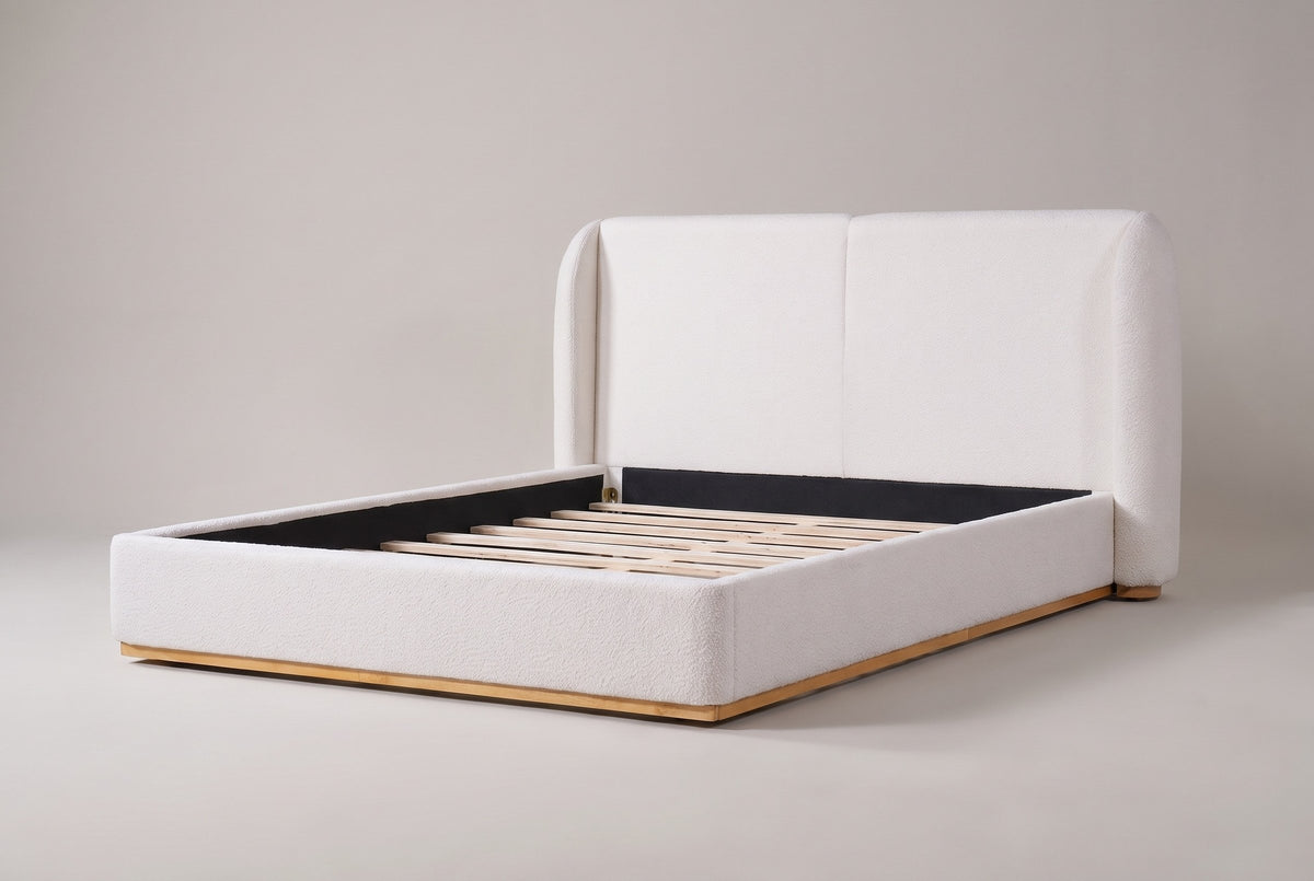 Varenna boucle wingback bed in white, three-quarter view on a warm grey studio backdrop, with its natural wood plinth