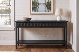 Black Velletri console table in the pine-panelled entry of a Muskoka lake cottage, a stoneware bowl and a white lamp on top