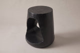 Venzone side table in Black, three-quarter view on a warm grey studio backdrop, the opening on its left side