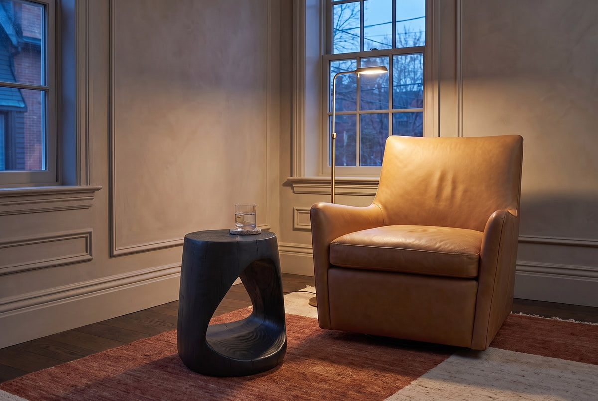 Venzone side table in Black beside a camel leather armchair in a Toronto sitting room at dusk, a brass floor lamp lit