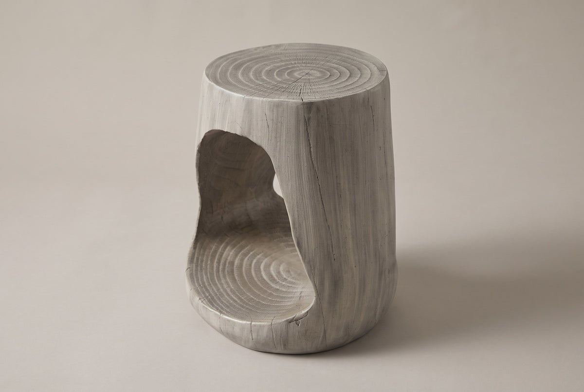 Venzone side table in Grey, three-quarter view on a warm grey studio backdrop, the opening on its left side