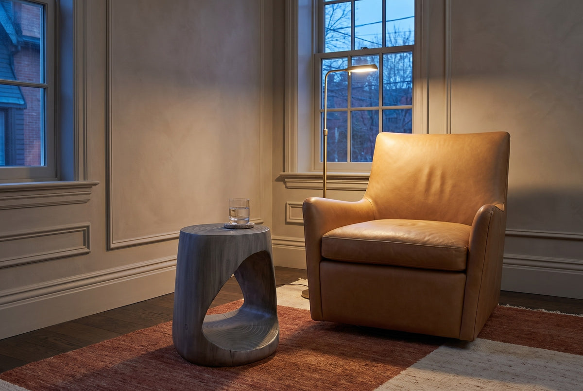 Venzone side table beside a camel leather armchair in a Toronto sitting room at dusk, a brass floor lamp lit