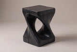 Vicenza twisted side table in Black, seen from the corner on a warm grey studio backdrop: square top, oval opening