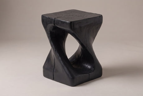 Vicenza twisted side table in Black, seen from the corner on a warm grey studio backdrop: square top, oval opening