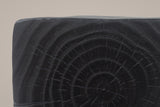 Close-up of the Black top corner: cast tree rings and radial cracks in charcoal black, the rounded edge