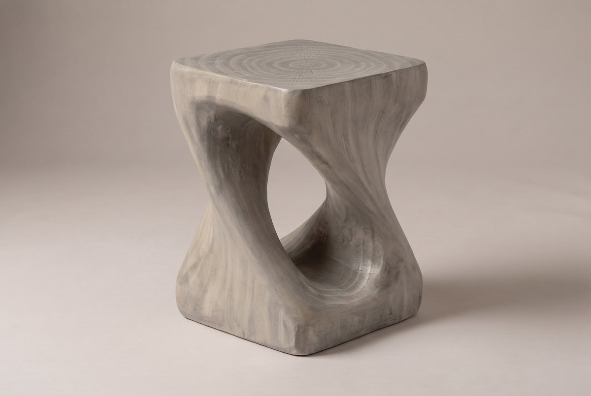 Vicenza twisted side table in Grey, seen from the corner on a warm grey studio backdrop: square top, oval opening