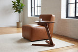 Vigevano side table in walnut beside a cognac leather chair in a Montreal loft with white brick walls, a white cup on top