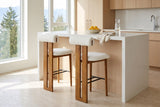 Two Vigoleno bar stools at a white quartz island in a bright Vancouver kitchen with pale oak cabinets and a bowl of lemons