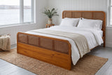 Vinci bed in a white board-panelled bedroom beside a window onto the harbour, with a jute rug and a wooden stool