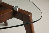 Close-up of a corner: a brushed-steel disc under the glass and the rail running into the top of the leg