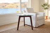 Vipiteno side table beside a white slipcovered armchair in a Kelowna lake house, the lake and hills through the window