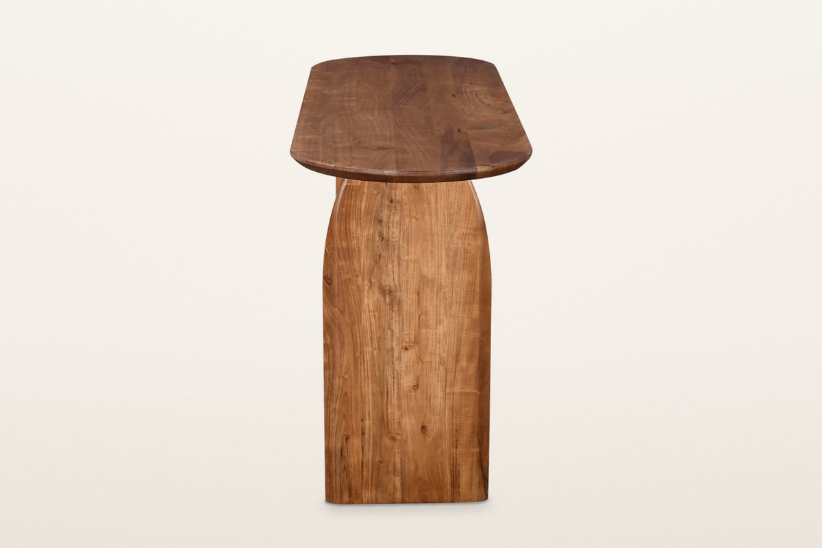 End view of the Visso console table in Pecan on a warm white studio backdrop: the arched face of a solid acacia panel leg und