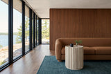 Vitorchiano side table in Natural White Washed at the arm of a cognac boucle sofa in a Falcon Lake house