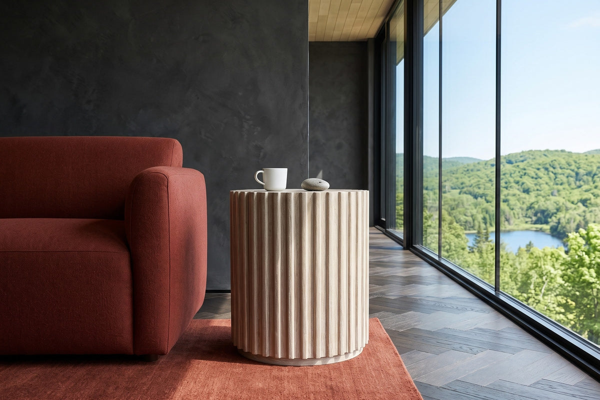 Side view of the Vitorchiano side table in Natural White Washed beside a rust-red sofa in a Morin-Heights house