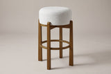 Vogogna backless bar stool in Dark Walnut with an ivory drum cushion, three-quarter view on a warm grey studio backdrop