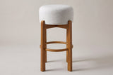 Vogogna bar stool in Walnut, straight front view on a studio backdrop: four square legs, a footring and a round drum seat