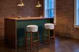 Two Vogogna bar stools at a green and walnut bar counter in a Toronto brick room under brass pendant lamps
