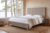 Volterra reeded bed in beige in a pine-panelled lakeside cottage bedroom with a jute rug