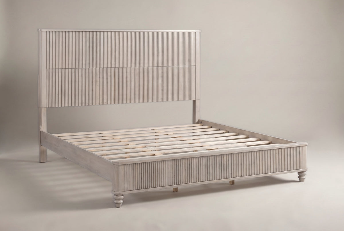 Volterra solid wood reeded bed in a pale whitewashed beige finish, three-quarter view on a warm off-white studio backdrop