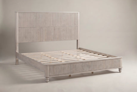 Volterra solid wood reeded bed in a pale whitewashed beige finish, three-quarter view on a warm off-white studio backdrop