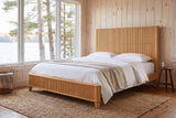 Volterra reeded bed in natural in a pine-panelled lakeside cottage bedroom with a jute rug