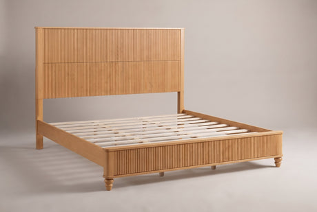 Volterra solid wood reeded bed in a natural honey finish, three-quarter view on a warm off-white studio backdrop