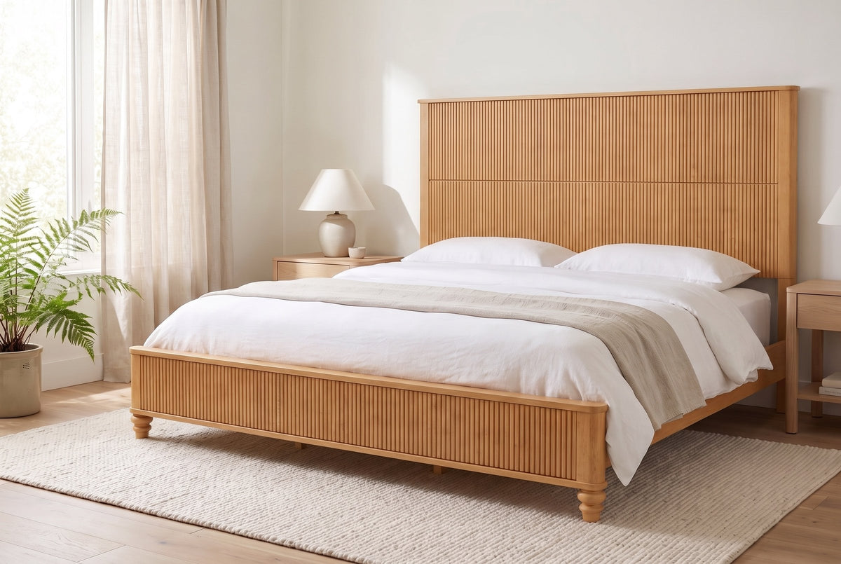Volterra reeded bed in natural made up with white linen, in a bright bedroom with a fern