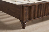 Close-up of the reeded footboard corner and a turned walnut bun foot on an oak floor