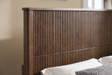 Close-up of the reeded walnut headboard, its flat capped top rail and square post