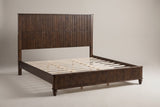 Volterra solid wood reeded bed in walnut, three-quarter view on a warm off-white studio backdrop