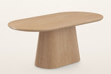 The Yale oval pedestal table in natural oak on its own, three-quarter view from above: the racetrack top on one wide reeded pedestal