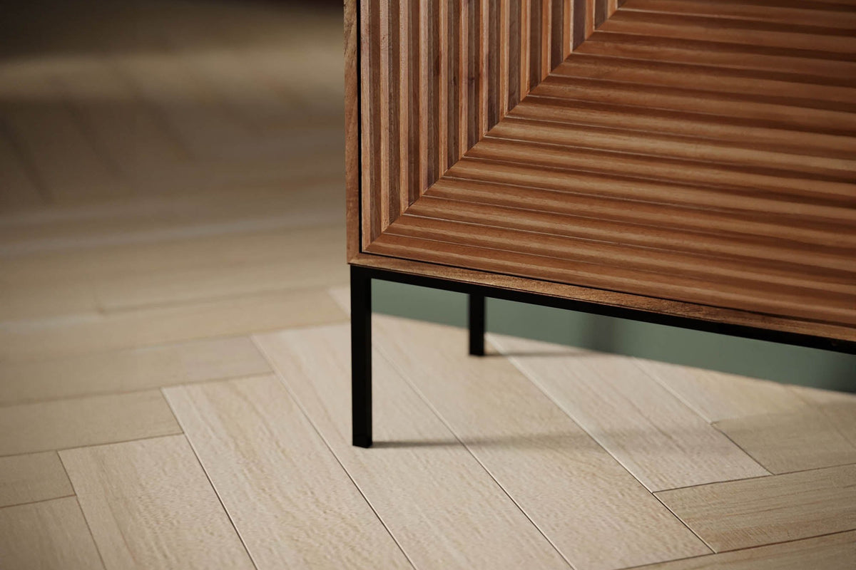 Black iron leg and fluted door of the Zephyr sideboard on a herringbone floor