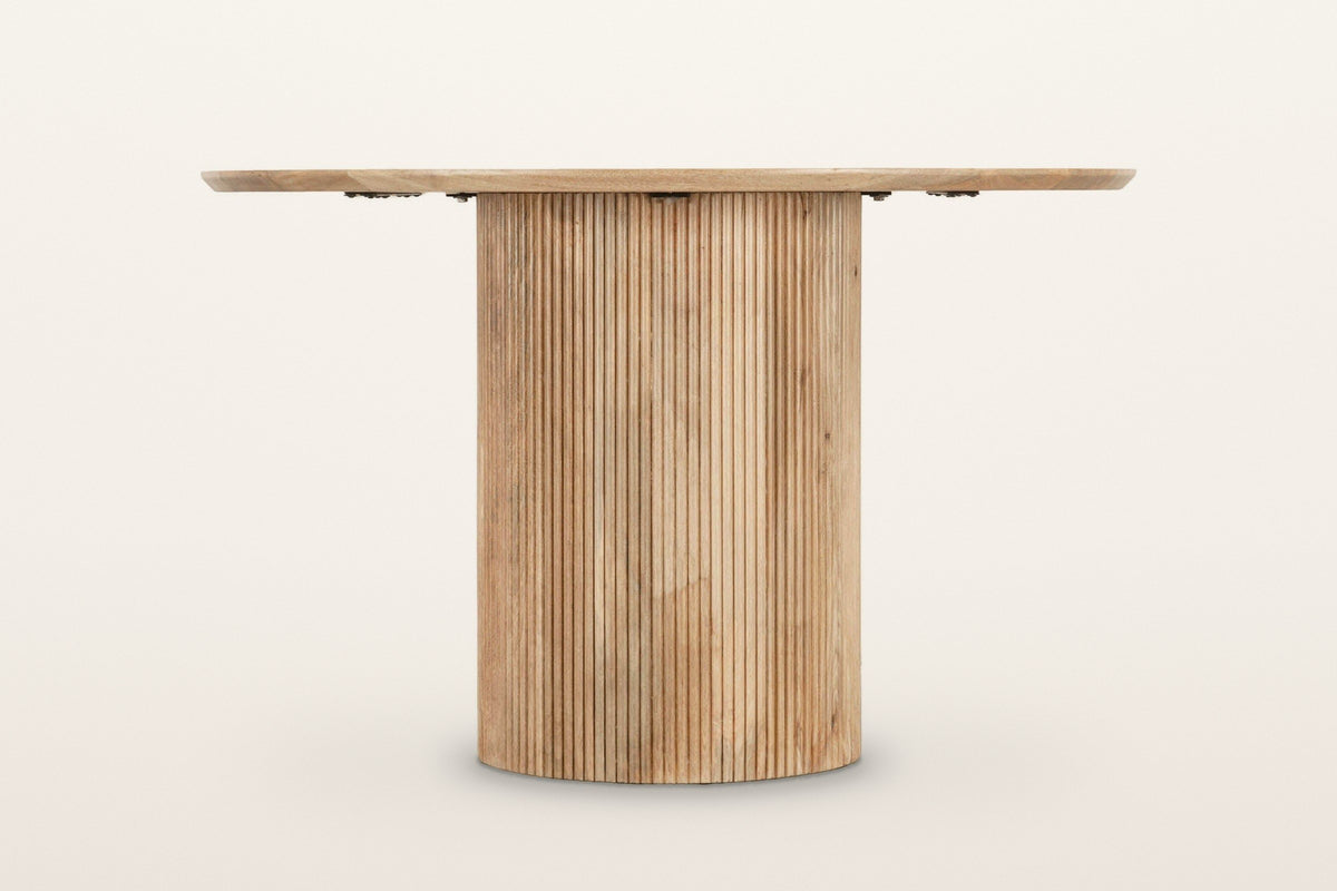Zuccarello dining table in Natural, level front view on a warm white studio backdrop: a straight reeded cylinder under a thin