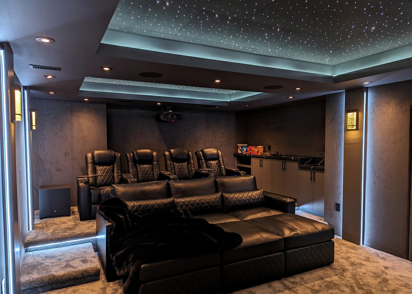 Gray home theater with black seating, a snack counter, and softly lit starlight ceiling panels